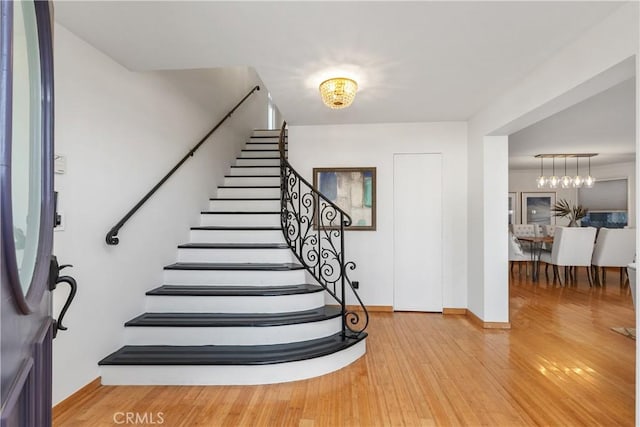 entryway with wood-type flooring and a notable chandelier