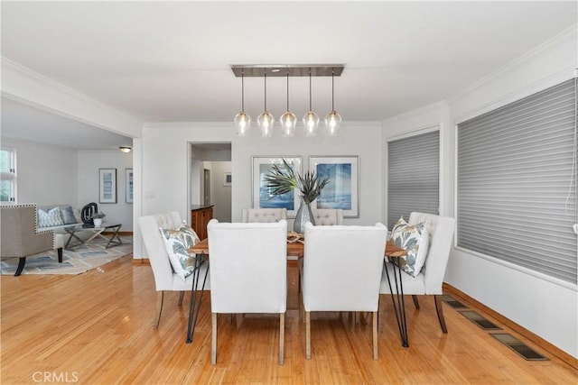 dining space featuring ornamental molding and light hardwood / wood-style floors