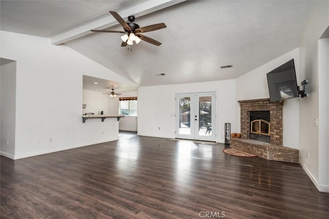 unfurnished living room with lofted ceiling with beams, a brick fireplace, dark wood-type flooring, and french doors