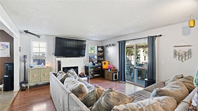 living room featuring a brick fireplace, a textured ceiling, and hardwood / wood-style floors