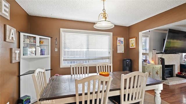 dining room featuring a fireplace, a textured ceiling, and hardwood / wood-style floors