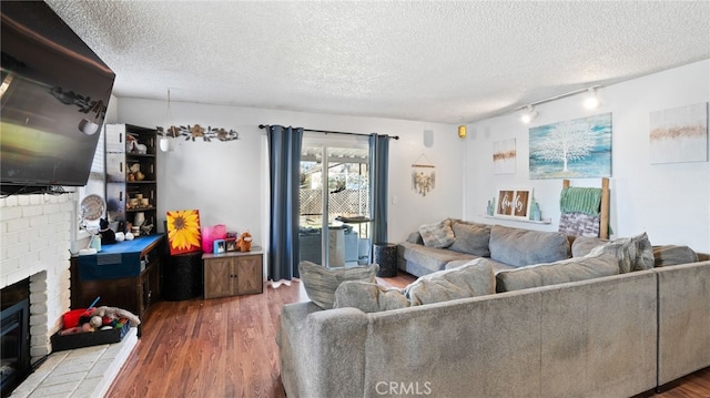 living room featuring a textured ceiling, track lighting, a fireplace, and hardwood / wood-style flooring