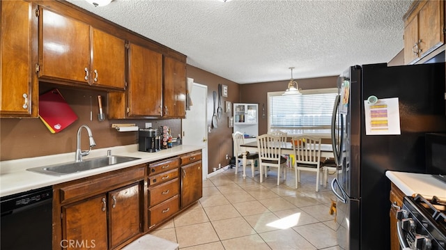 kitchen with a textured ceiling, black appliances, sink, hanging light fixtures, and light tile patterned floors