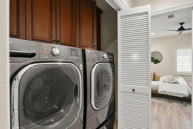 washroom with washing machine and dryer, cabinets, light wood-type flooring, and ceiling fan