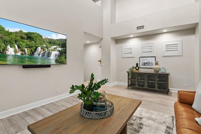 living room featuring a towering ceiling and light hardwood / wood-style flooring