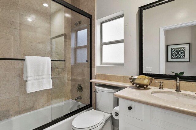 full bathroom with toilet, enclosed tub / shower combo, and vanity