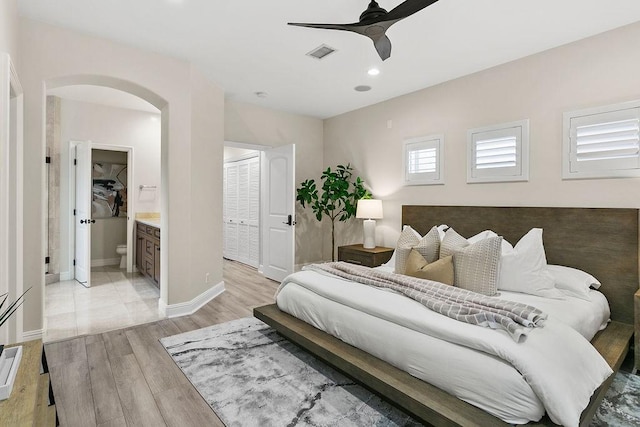 bedroom with ceiling fan, connected bathroom, and light hardwood / wood-style flooring