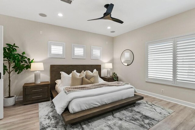 bedroom with ceiling fan, multiple windows, and light hardwood / wood-style floors