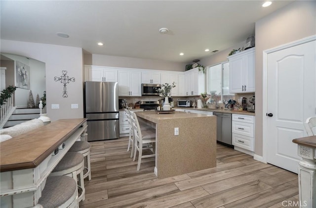 kitchen featuring white cabinetry, appliances with stainless steel finishes, a center island, and backsplash