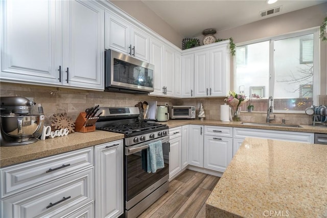 kitchen featuring white cabinetry, sink, backsplash, and stainless steel appliances