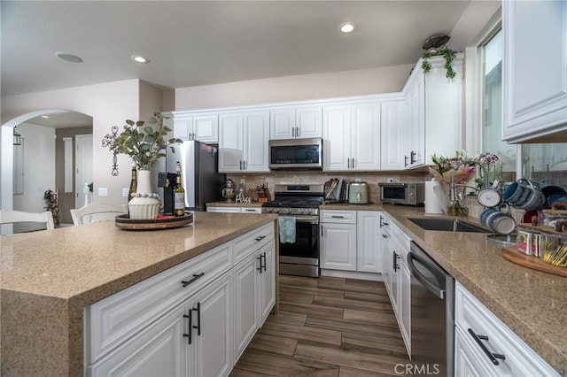 kitchen featuring white cabinetry, decorative backsplash, a kitchen island, and appliances with stainless steel finishes