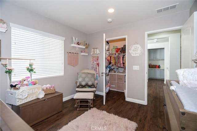 interior space featuring a walk in closet, dark hardwood / wood-style flooring, and a closet