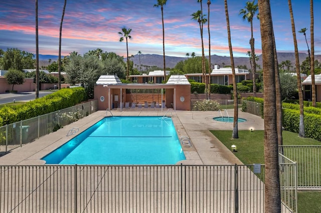 pool at dusk featuring a mountain view and a patio area