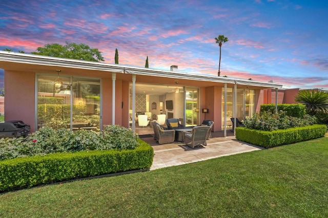 back house at dusk with a yard and a patio