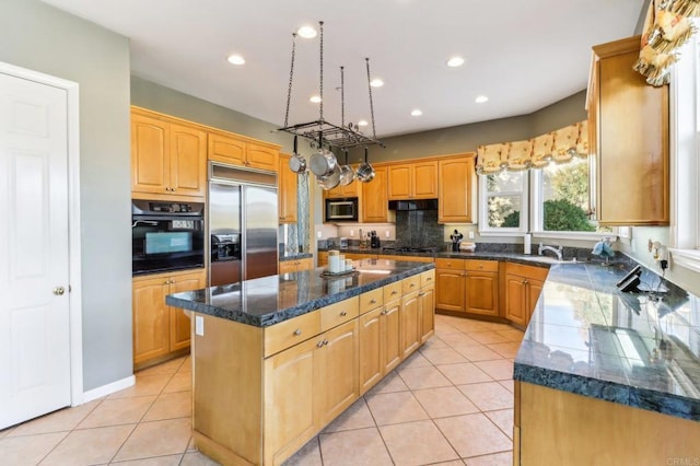 kitchen featuring a center island, black appliances, dark stone countertops, sink, and light tile patterned flooring