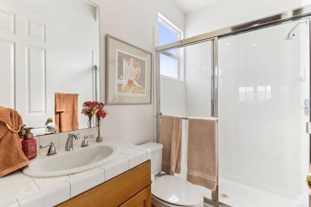 bathroom featuring toilet, a shower with shower door, and vanity