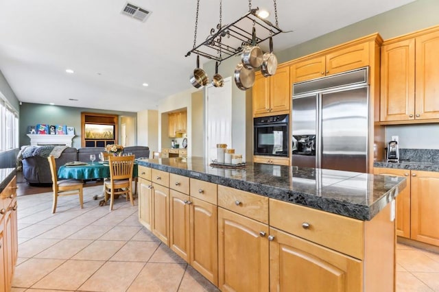 kitchen with built in refrigerator, light tile patterned floors, oven, and a center island