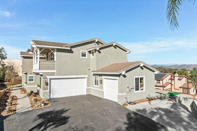 view of front facade with a garage, a mountain view, and a balcony