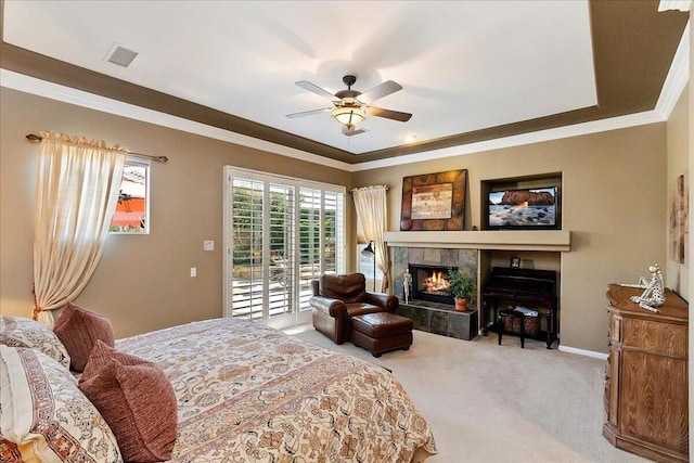 bedroom with carpet floors, a tiled fireplace, ornamental molding, access to exterior, and ceiling fan