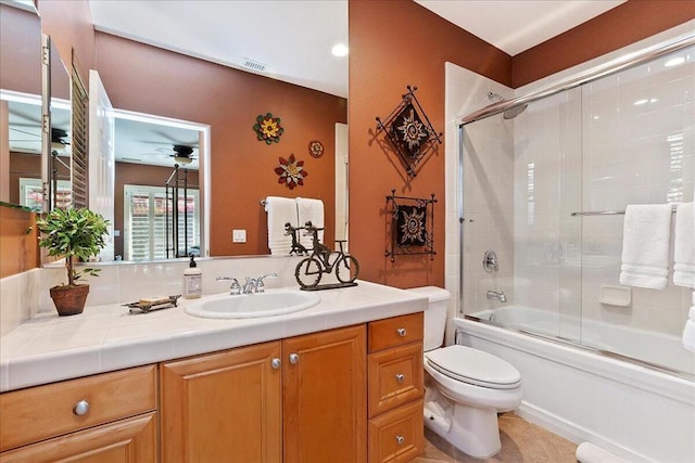 full bathroom featuring toilet, ceiling fan, vanity, and shower / bath combination with glass door