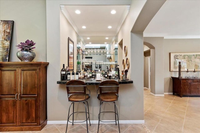 bar with crown molding, dark stone countertops, and light tile patterned flooring