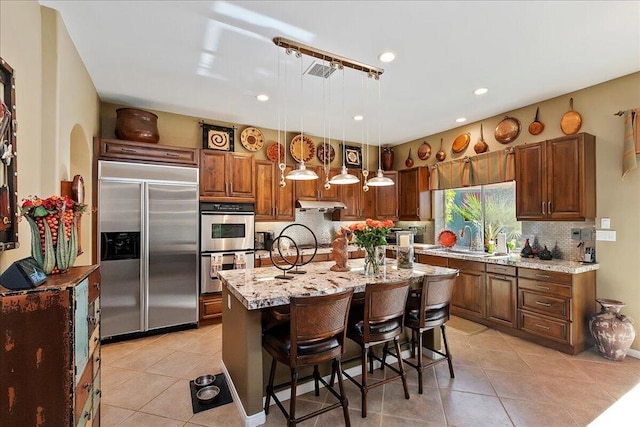 kitchen featuring stainless steel appliances, light tile patterned flooring, a kitchen island, and pendant lighting