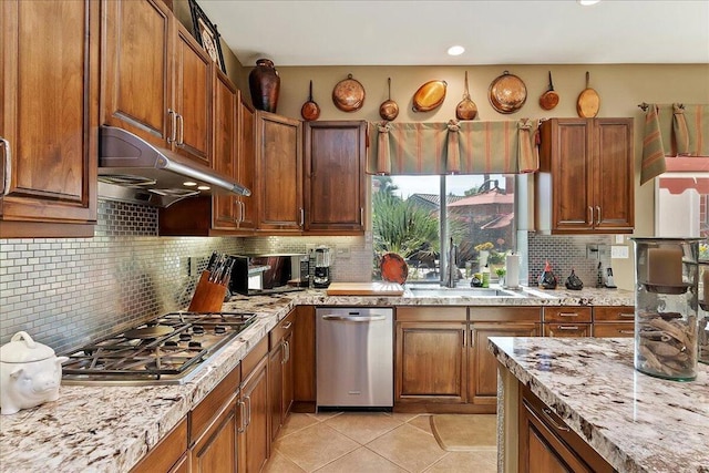 kitchen with sink, stainless steel gas cooktop, light tile patterned floors, light stone countertops, and decorative backsplash