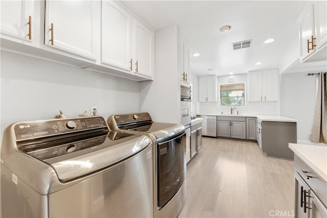 washroom with sink, light hardwood / wood-style flooring, and washing machine and clothes dryer