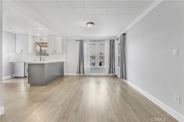 unfurnished living room with sink, light hardwood / wood-style flooring, and a healthy amount of sunlight