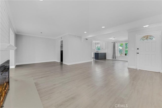 unfurnished living room featuring a large fireplace, ornamental molding, and light hardwood / wood-style flooring