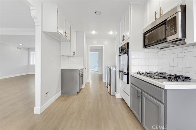 kitchen with stainless steel appliances, light hardwood / wood-style flooring, white cabinets, and tasteful backsplash