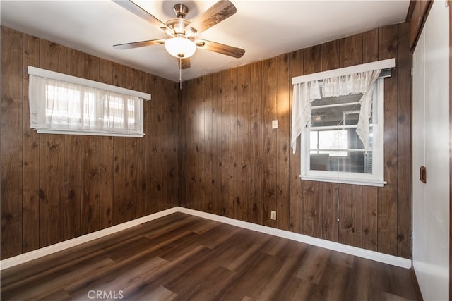 empty room featuring dark hardwood / wood-style flooring, a healthy amount of sunlight, and wooden walls