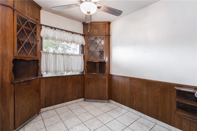 unfurnished dining area featuring ceiling fan and wooden walls