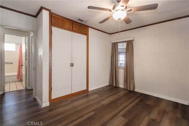 unfurnished bedroom featuring dark wood-type flooring, ceiling fan, crown molding, and a closet