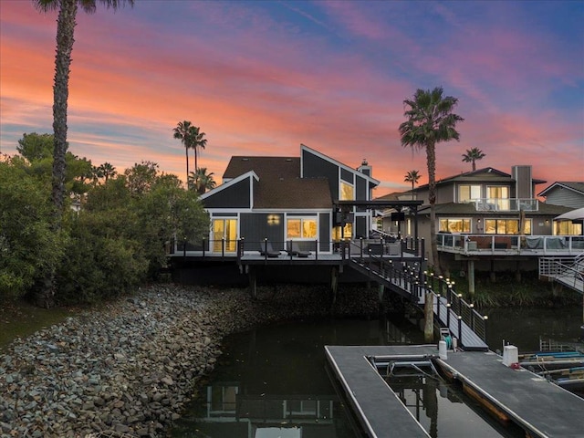 back house at dusk with a deck with water view