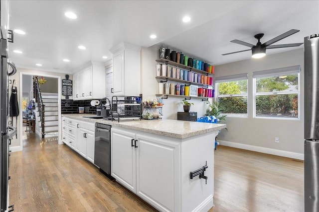 kitchen with light stone counters, appliances with stainless steel finishes, light hardwood / wood-style floors, and white cabinets