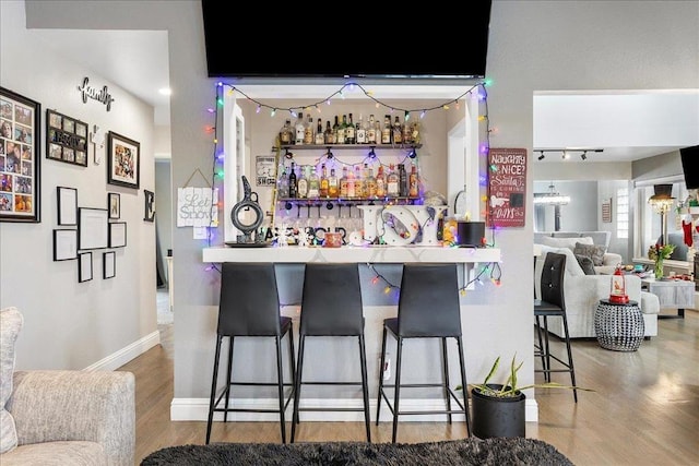 bar with track lighting and wood-type flooring