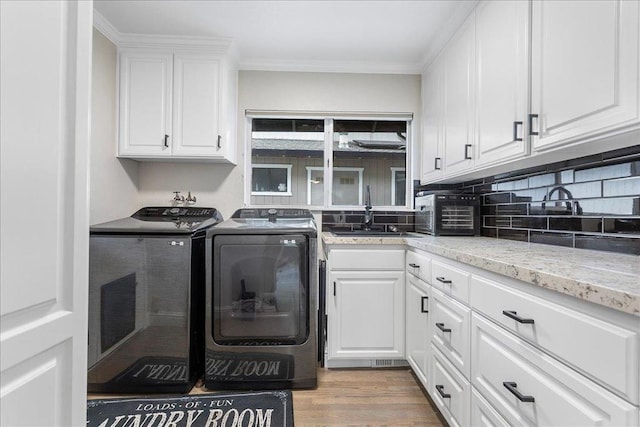 washroom with sink, cabinets, independent washer and dryer, light hardwood / wood-style floors, and crown molding