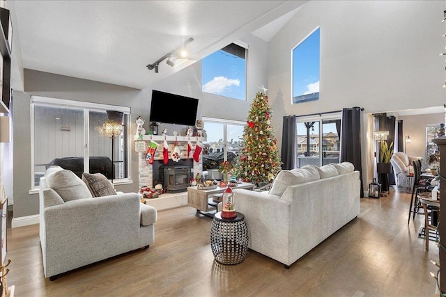 living room featuring track lighting, a fireplace, hardwood / wood-style floors, and a high ceiling