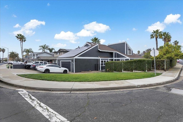 view of front facade featuring a garage, a front yard, and solar panels