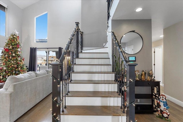 stairway with a towering ceiling and wood-type flooring