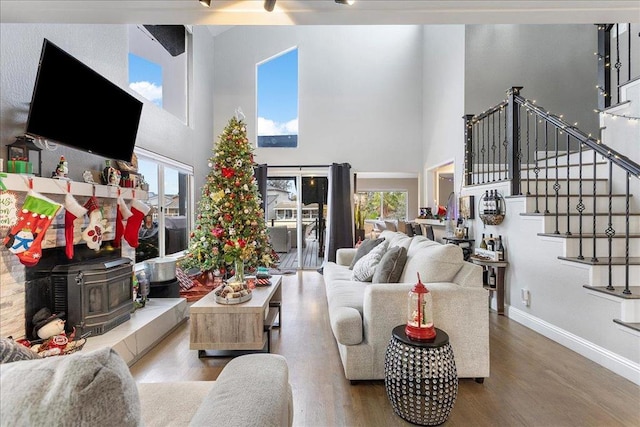 living room featuring wood-type flooring, a wood stove, and a wealth of natural light