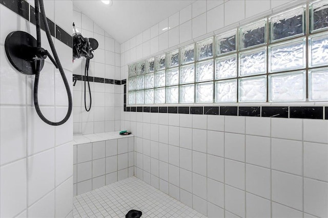 bathroom featuring lofted ceiling and tiled shower