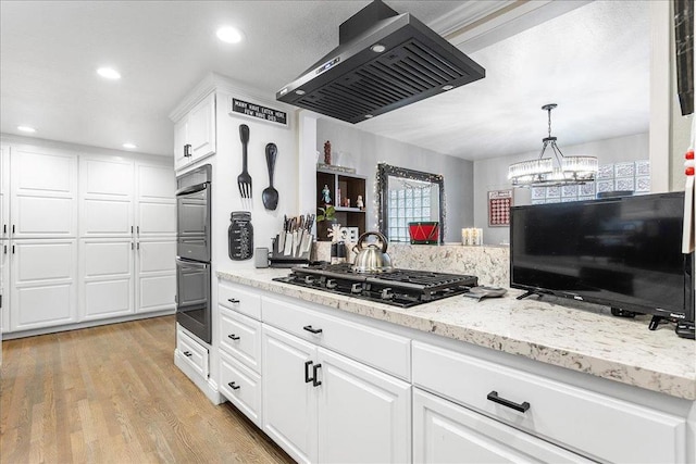 kitchen featuring decorative light fixtures, range hood, white cabinets, black appliances, and light wood-type flooring