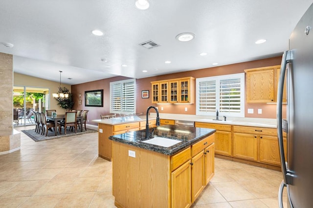 kitchen featuring appliances with stainless steel finishes, lofted ceiling, sink, hanging light fixtures, and a center island with sink