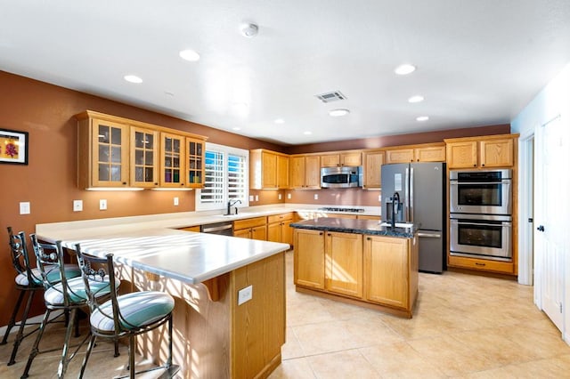 kitchen with a kitchen island, a breakfast bar, light tile patterned flooring, sink, and stainless steel appliances