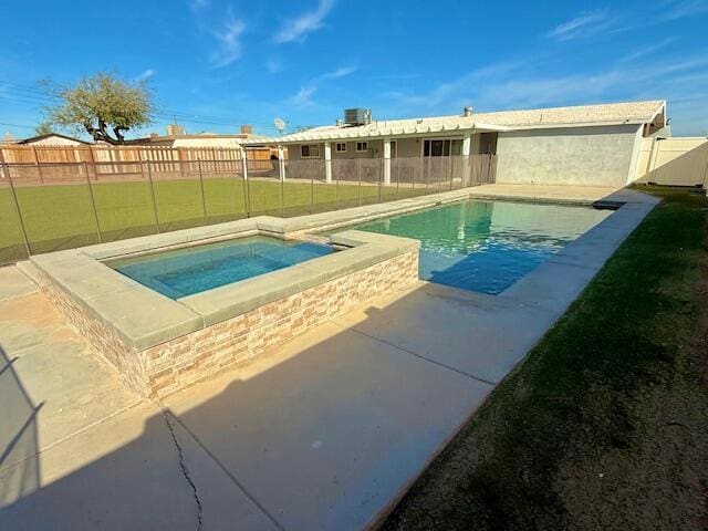 view of swimming pool featuring a lawn and an in ground hot tub