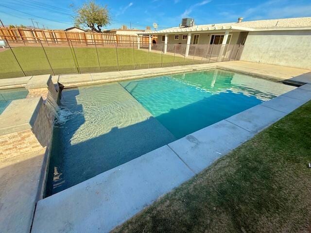 view of swimming pool with a lawn and central air condition unit