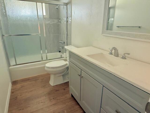 full bathroom featuring toilet, vanity, combined bath / shower with glass door, and hardwood / wood-style flooring