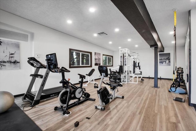 exercise room featuring a textured ceiling and light hardwood / wood-style flooring